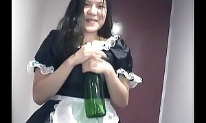 Young Asian girl dressed as A a maid indulges herself around a bottle of champagne on camera for you